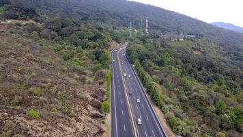 ripresa aerea di auto elettrica che guida su strada di campagna in serata estiva. nuovo veicolo suv che si muove velocemente attraverso l'autostrada. auto ecologica che viaggia a carica elettrica lungo l'autostrada. vista dall'alto video