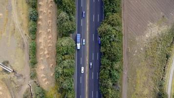 Aerial shot of electrical car driving on country road at summer evening. New SUV vehicle moving fast through highway. Ecology friendly auto riding on electric charge along motorway. Top view video