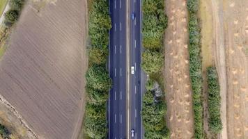 Aerial shot of electrical car driving on country road at summer evening. New SUV vehicle moving fast through highway. Ecology friendly auto riding on electric charge along motorway. Top view video