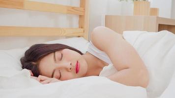 mujer asiática soñando mientras duerme en la cama en el dormitorio, hermosa mujer japonesa usando tiempo de relajación acostada en la cama en casa. mujeres de estilo de vida que usan el concepto de tiempo de relajación en casa. foto