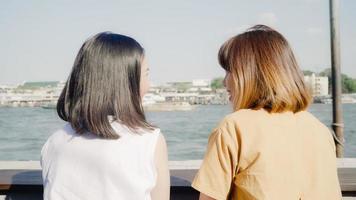 Las jóvenes asiáticas, amigas cercanas, turistas con casuales, disfrutan hablando de chismes frente al barco del puerto en el río, se sienten felices y alegres viajando en el café de la ciudad, concepto de vacaciones de viaje turístico de estilo de vida. foto