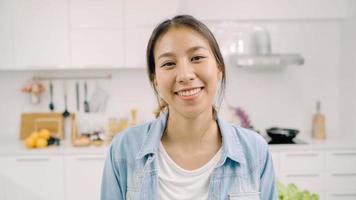 retrato de una joven latina asiática que se siente feliz sonriendo en casa. la chica hispana se relaja con una sonrisa dentuda mirando a la cámara en la cocina de casa por el concepto de la mañana. foto