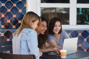 grupo de hermosas mujeres asiáticas independientes de negocios inteligentes con ropa informal inteligente que trabajan juntas en una computadora portátil o computadora mientras se sientan en la mesa en una oficina creativa o café. foto