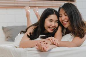 Asian Lesbian lgbtq women couple kiss and hug on bed at home. Young Asia lover female happy relax rest together spend romantic time after wake up in bedroom at home in the morning concept. photo