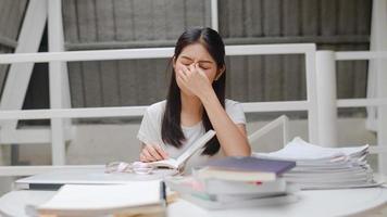 Asian student women read books in library at university. Young undergraduate girl stress tired have problem while study hard for knowledge on lecture desk at college campus concept. photo