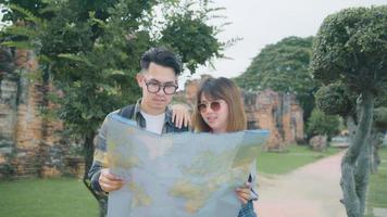 Traveler Asian couple direction and looking on location map while spending holiday trip at Ayutthaya, Thailand, backpacker couple enjoy journey in traditional city. Lifestyle couple travel concept. photo