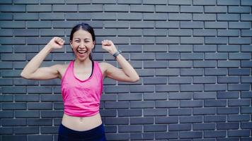 saludable y hermosa joven corredora asiática que se siente feliz sonriendo y mirando a la cámara después de correr en la calle en la ciudad urbana. estilo de vida en forma y mujeres activas hacen ejercicio en el concepto de ciudad. foto
