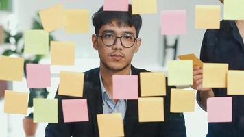 taller de grupo de hombres creativos asiáticos y lluvia de ideas frente al tablero de espejos. joven equipo profesional de negocios que trabaja para crear estrategia, situación comercial, puesta en marcha en el concepto de oficina de loft. foto