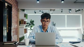 hombre creativo asiático dibujando un plan de trabajo en un tablero de papel. un joven profesional de negocios piensa y escribe un recordatorio de información en papel sobre ladrillo, situación comercial, puesta en marcha en el concepto de oficina de loft. foto