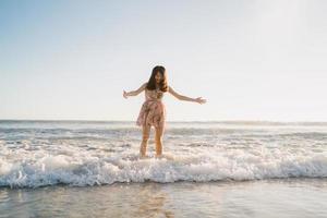 Young Asian woman walking on beach. Beautiful female happy relax walking on beach near sea when sunset in evening. Lifestyle women travel on beach concept. photo