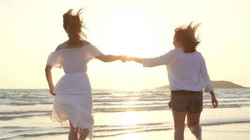 joven pareja de lesbianas asiáticas corriendo en la playa. hermosas amigas felices se relajan divirtiéndose en la playa cerca del mar cuando se pone el sol por la noche. estilo de vida pareja de lesbianas viaja en concepto de playa. foto