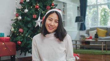 las mujeres asiáticas celebran el festival de navidad. Las adolescentes usan sombrero de Navidad, se relajan, sonríen feliz, miran la cámara, disfrutan de las vacaciones de invierno de Navidad juntas en la sala de estar en casa. foto