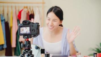 Beauty blogger present beauty cosmetics sitting in front camera for recording video. Beautiful asian woman use cosmetics review make up tutorial broadcast live video to social network by internet. photo