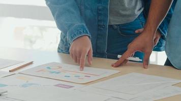 reunión del equipo creativo asiático joven que trabaja en la computadora portátil. grupo de hombres y mujeres de negocios que buscan papel de documento, discuten y piensan en nuevas ideas, situación de negocios, trabajo en equipo en el concepto de oficina moderna. foto