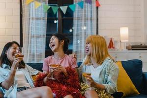 Group of Asian women party at home, female drinking cocktail talking having funny together on sofa in living room in night. Teenager young friend play game, friendship, celebrate holiday concept. photo