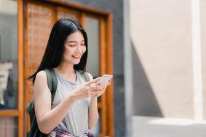 Traveler Asian woman direction on location map in Beijing, China, backpacker female using mobile phone looking on map find landmark while holiday trip. Lifestyle women travel in city concept photo