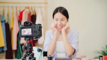 Beauty blogger present beauty cosmetics sitting in front camera for recording video. Beautiful asian woman use cosmetics review make up tutorial broadcast live video to social network by internet. photo