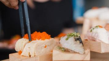 Asian woman eating sushi in japanese restaurant, young female holding chopsticks and eating salmon sushi in lunch time in summer. Lifestyle women eating traditional food concept. photo