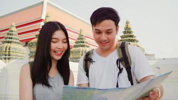 Traveler Asian couple direction on location map in Bangkok, Thailand, sweet Asia couple looking on map find landmark while spending holiday trip. Lifestyle couple travel in city concept. photo