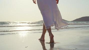 Young Asian woman walking on beach. Beautiful female happy relax walking on beach near sea when sunset in evening. Lifestyle women travel on beach concept. photo