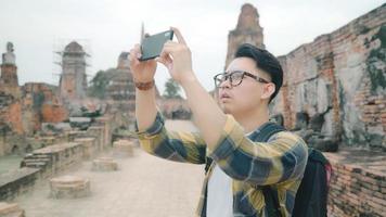 Traveler Asian man using smartphone for take a picture while spending holiday trip at Ayutthaya, Thailand, Male enjoy his journey at amazing landmark in traditional city. photo