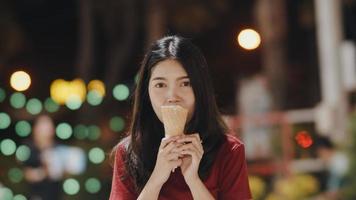 Asian young woman travel in Bangkok, Thailand, beautiful female feeling happy walking and eating ice cream at The Khao San Road. Women travel eat street food in Thailand concept. photo