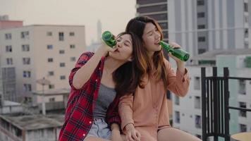 Group of young asian women people dancing and raising their arms up in air to the music played by dj at sunset urban party on rooftop. Young asian girls friends hanging out with drinks. photo