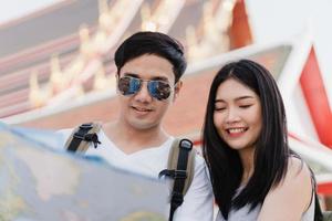 Traveler Asian couple direction on location map in Bangkok, Thailand, sweet Asia couple looking on map find landmark while spending holiday trip. Lifestyle couple travel in city concept. photo