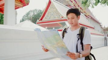 Traveler Asian man direction on location map in Bangkok, Thailand, backpacker male looking on map find landmark while spending holiday trip. Lifestyle men travel in Asia city concept. photo