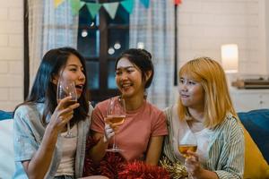 Group of Asian women party at home, female drinking cocktail talking having funny together on sofa in living room in night. Teenager young friend play game, friendship, celebrate holiday concept. photo