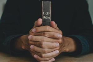 Hands of a man praying over a Bible represents faith and spirituality in everyday life. close up. photo