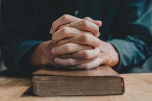 las manos de un hombre que reza sobre una biblia representan la fe y la espiritualidad en la vida cotidiana. de cerca. foto