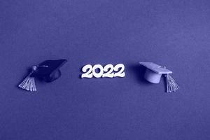 Graduation cap and numbers 2022 on very peri background, closeup with copy space. Medical education concept. photo