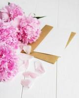 invitation card, craft envelope and pink peony flowers photo