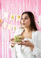 hermosa mujer celebrando la fiesta de cumpleaños sosteniendo un trozo de pastel pidiendo un deseo foto