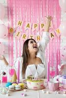 hermosa mujer emocionada celebrando la fiesta de cumpleaños lanzando confeti rosa foto