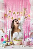 Beautiful excited woman celebrating birthday party throwing pink confetti photo