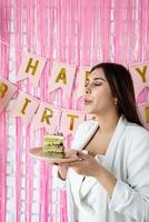 Beautiful excited woman celebrating birthday holding cake making wish photo