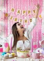Beautiful excited woman celebrating birthday party throwing pink confetti photo