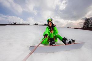 Beautiful woman using smartphone to making selfie with a snowboard on a ski slope photo