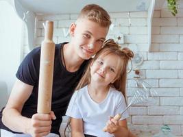 caucasian funny cute siblings in kitchen -  little girl with older brother baking in kitchen. Bake and culinary concept photo