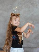 caucasian funny adorable cute little girl playing like cat with soap bubbles on gray background photo