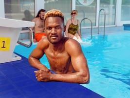 hombre afroamericano con mujer caucásica en la piscina. verano. concepto de vacaciones, diversidad y deporte. foto