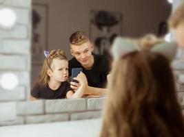 portrait of adorable beautiful caucasian siblings making selfie in the make up mirror. Family, beauty, casting and children concept photo