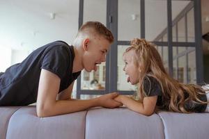 caucasian siblings - teenager boy brother and little girl sister playing in aircraft in modern loft interior on gray cement background photo