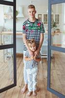 stylish caucasian siblings in striped t-shirts and white pants standing in loft interior. Family, fashion, relatives, relationship and children concept. photo