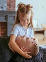 hermanos caucásicos - hermano adolescente y hermana pequeña sentados en un sofá en un moderno interior de loft foto