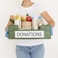 voluntaria con guantes sosteniendo una caja de donación de alimentos foto