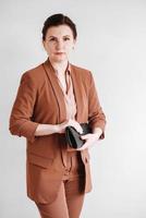 Woman dressed in a brown business suit with a black handbag on a white background. Copy, empty space photo