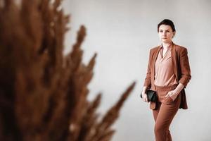 Woman dressed in a brown business suit with a black handbag on a white background. Copy, empty space photo